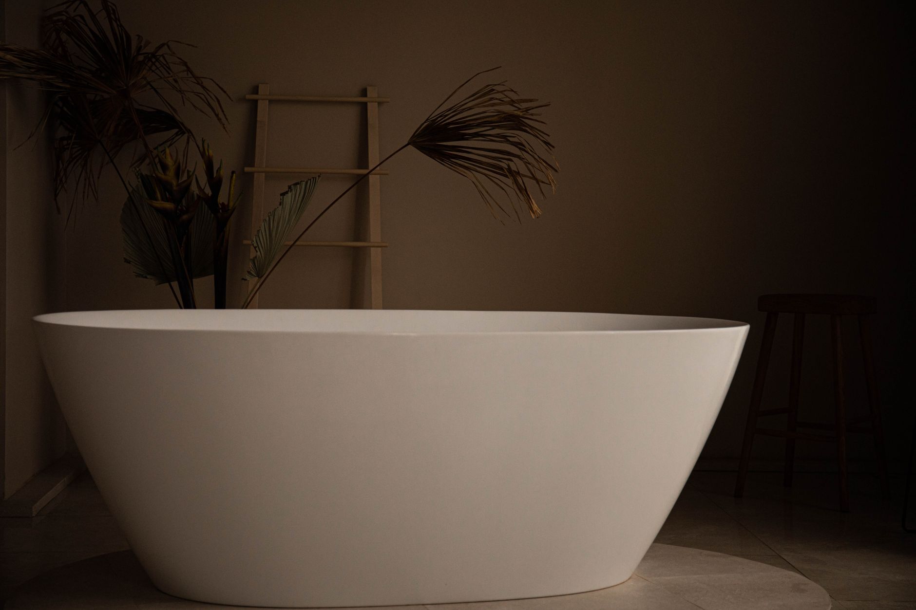 phòng tắm spa tại nhà với bình chiết sứ cốc sứ và khay oval trên nền đá marble tối giản