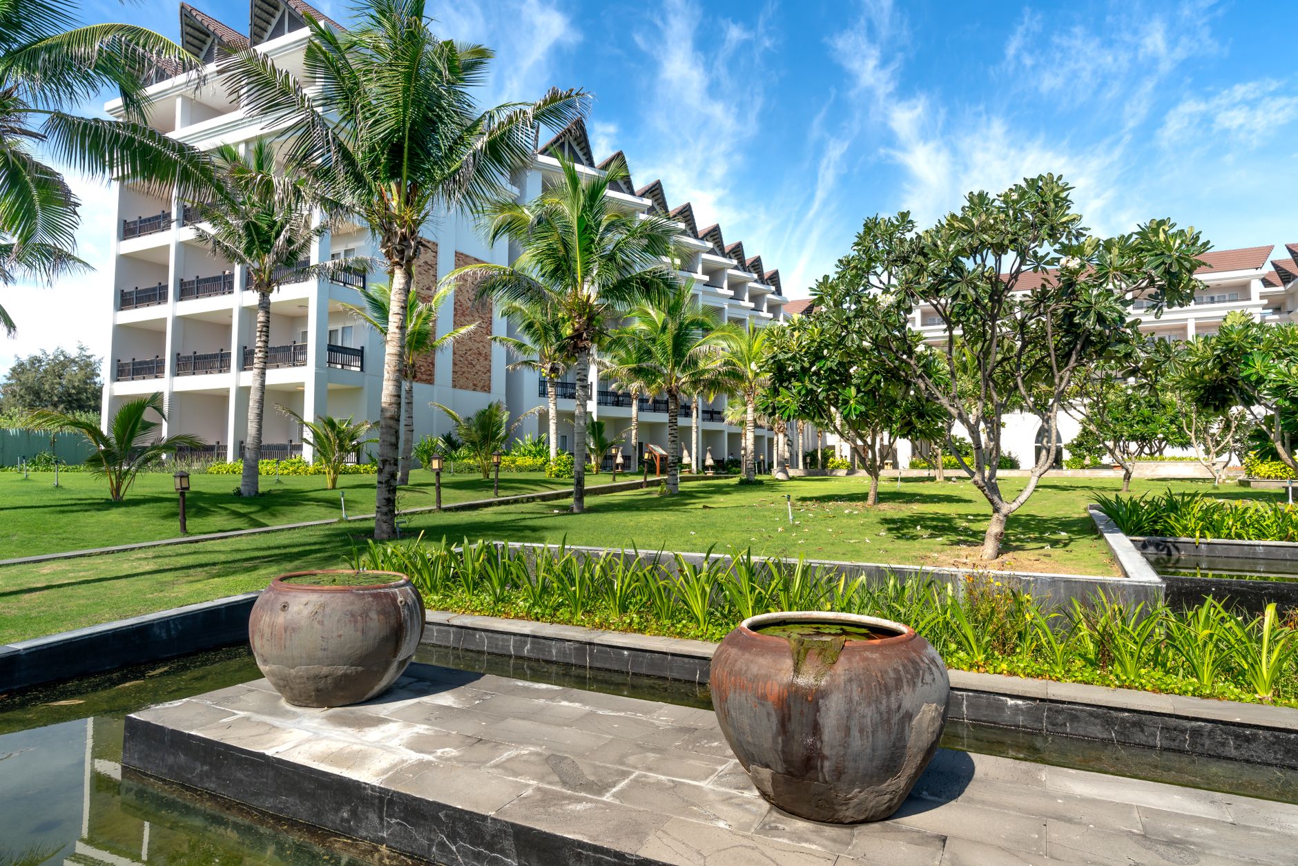 Bộ amenity gốm sứ Bát Tràng men trắng ngà xếp trên khay gỗ tre trong phòng resort ven biển, ánh sáng ban mai tự nhiên