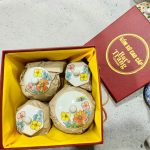 Hộp quà gốm sứ Bát Tràng thủ công men mờ trắng ngà trên nền vải linen, ruy băng hồng, ánh sáng tự nhiên ấm