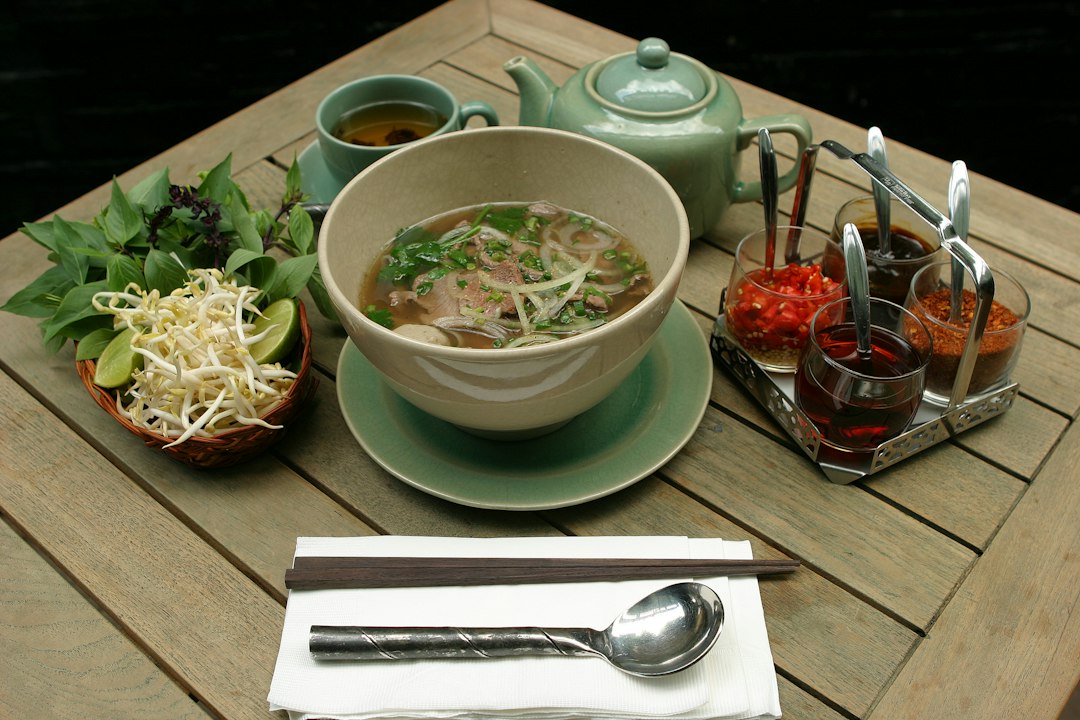 Bộ chén bát đĩa sứ Bát Tràng Linh Miêu trên bàn nhà hàng ẩm thực Việt — men trắng ngà tinh tế, đồng bộ phong cách