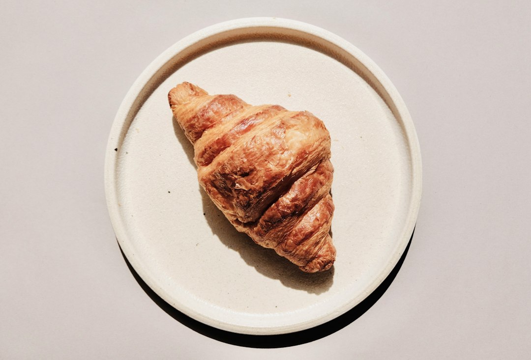 Đĩa sứ Bát Tràng Linh Miêu đựng bánh croissant và macaron trong không gian cafe tối giản